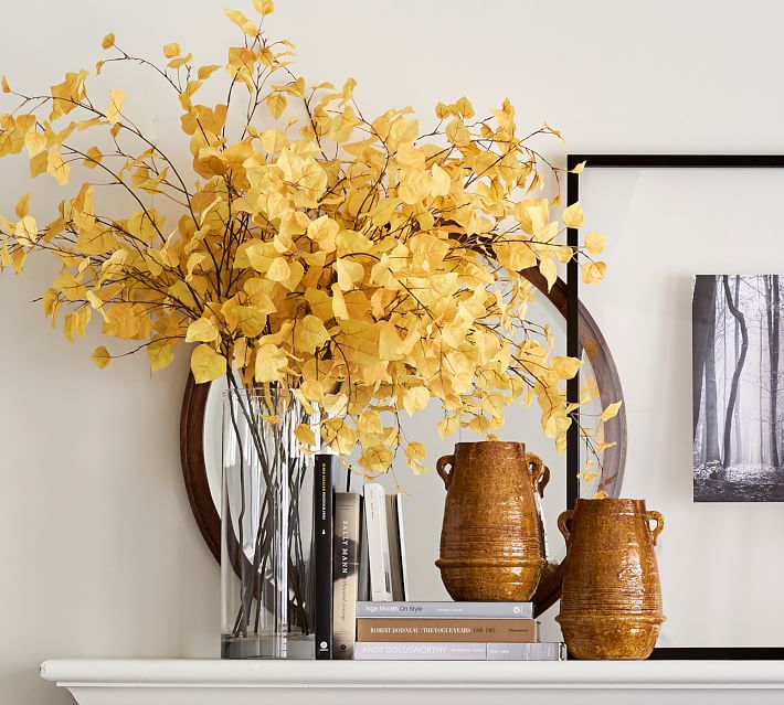 Revealing Pantone's 2021 colors of the year illuminating yellow and ultimate grey with yellow flower stems in a glass vase on a white fireplace mantel
