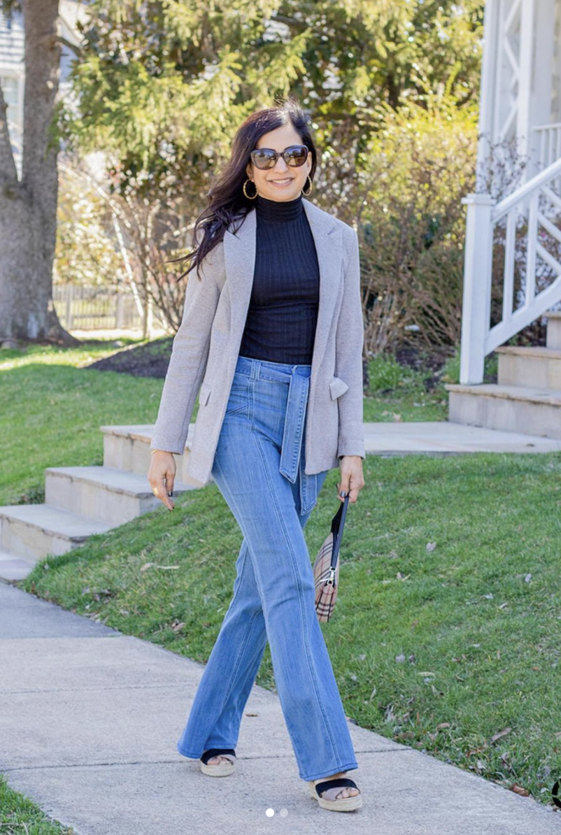 Styling Blazers Over 40, Sapna Delacourt from Lunch with A Girlfriend wearing a long beige blazer with black turtleneck, flared jeans, and wedges