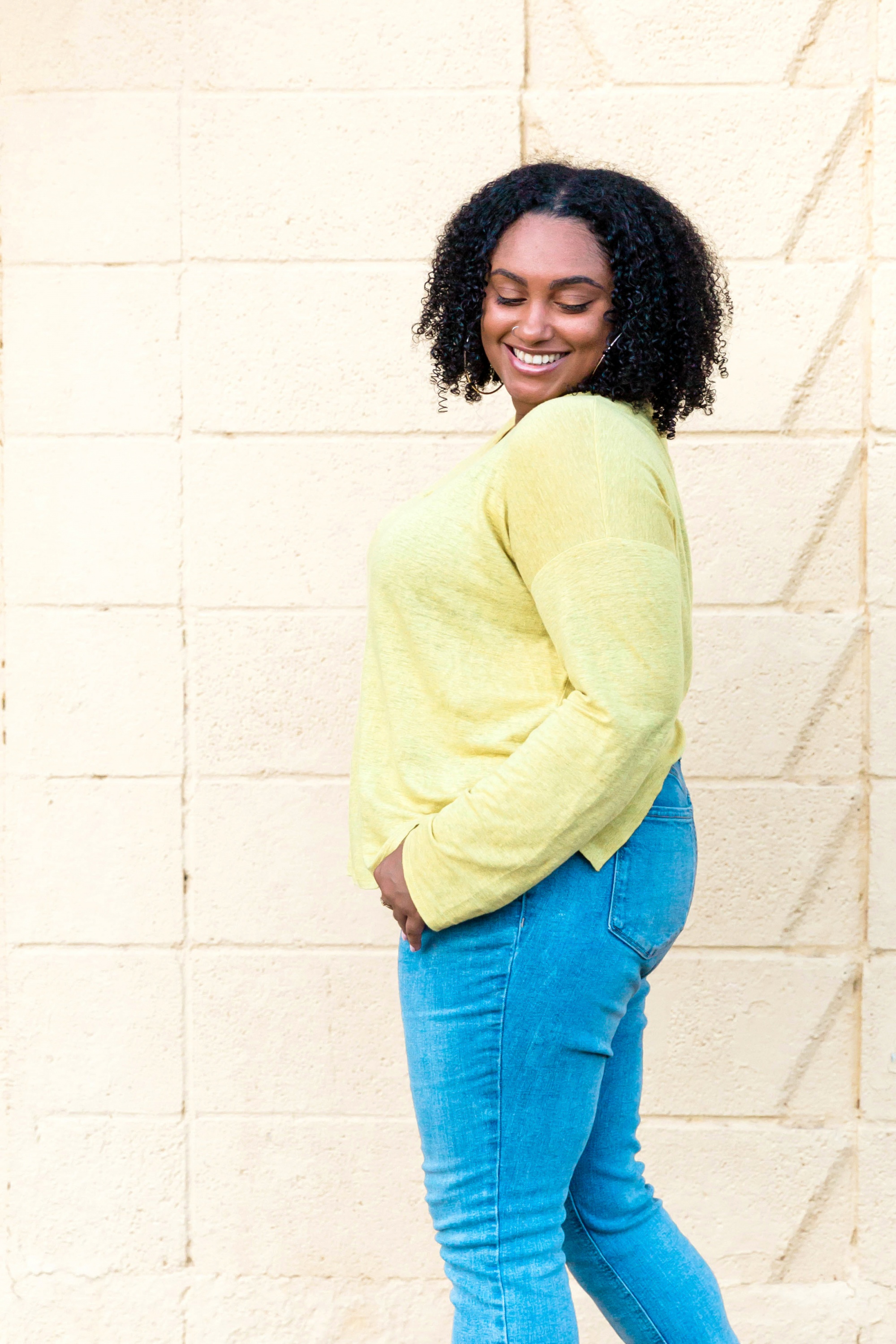Embrace negative thoughts and turn them into joy, Smiling Black woman with chin-length curls in yellow sweater and jeans