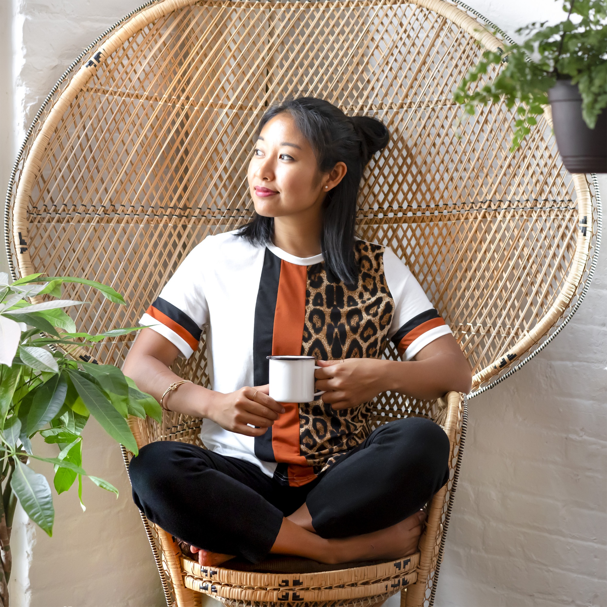 self-care and self-love, asian woman sitting crosslegged in rattan chair holding mug and thinking positive thoughts