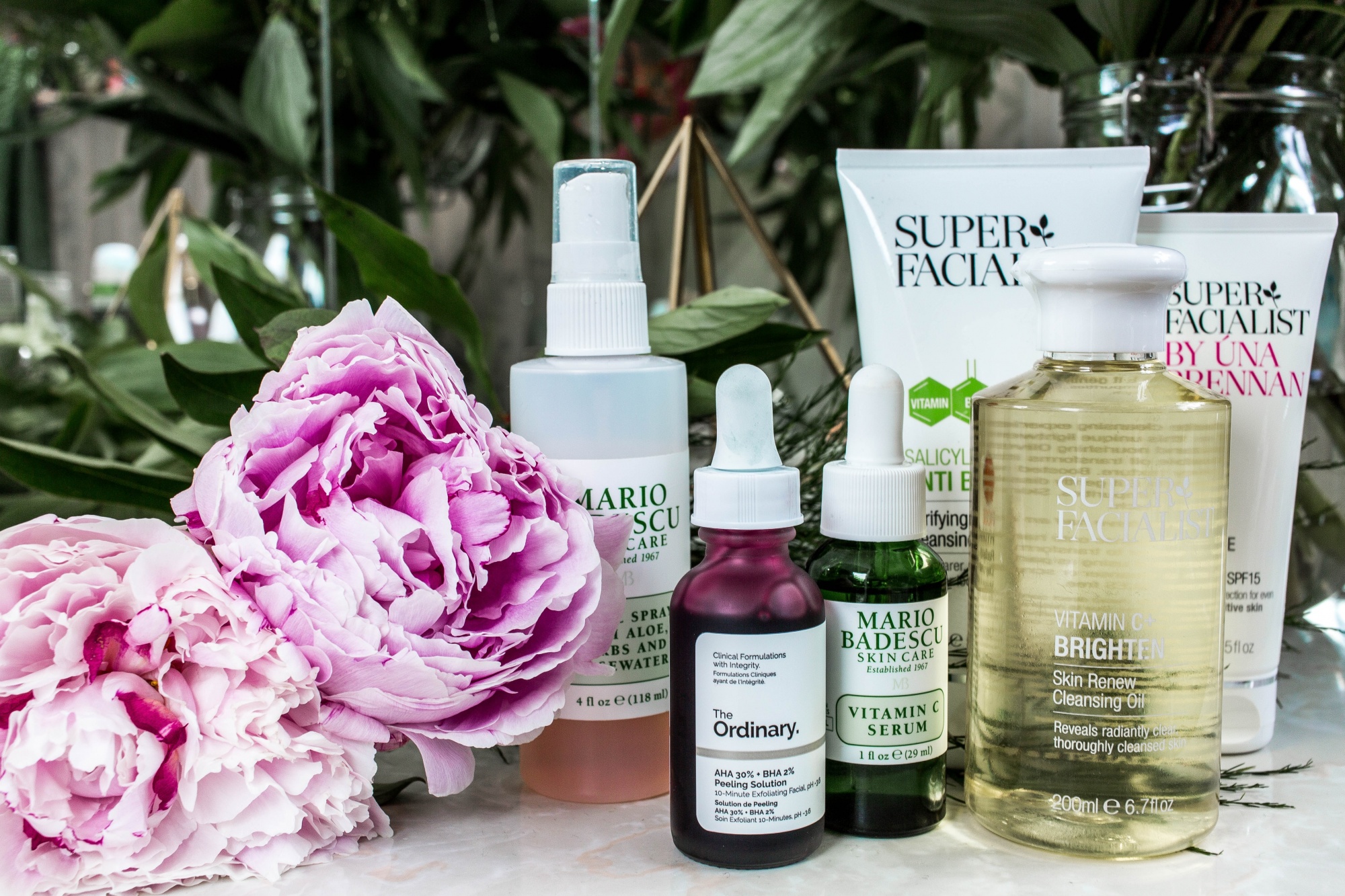 how to reduce hyperpigmentation, hyperpigmentation solutions various bottles on a table with flowers including products by Mario Badescu, The Ordinary, and more