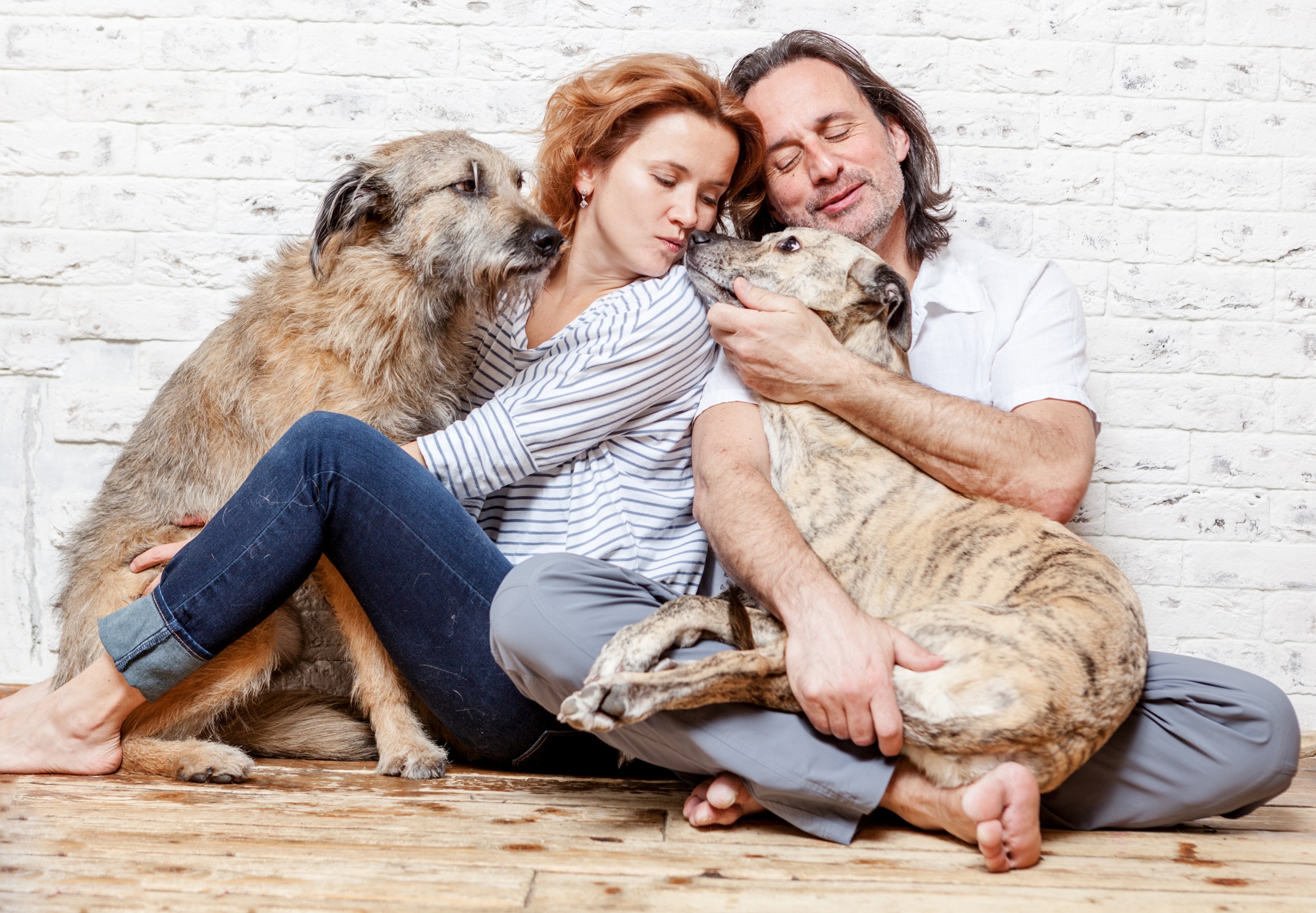 dogs save empty nesters, middle aged couple sitting relaxed on the floor snuggling with their dogs