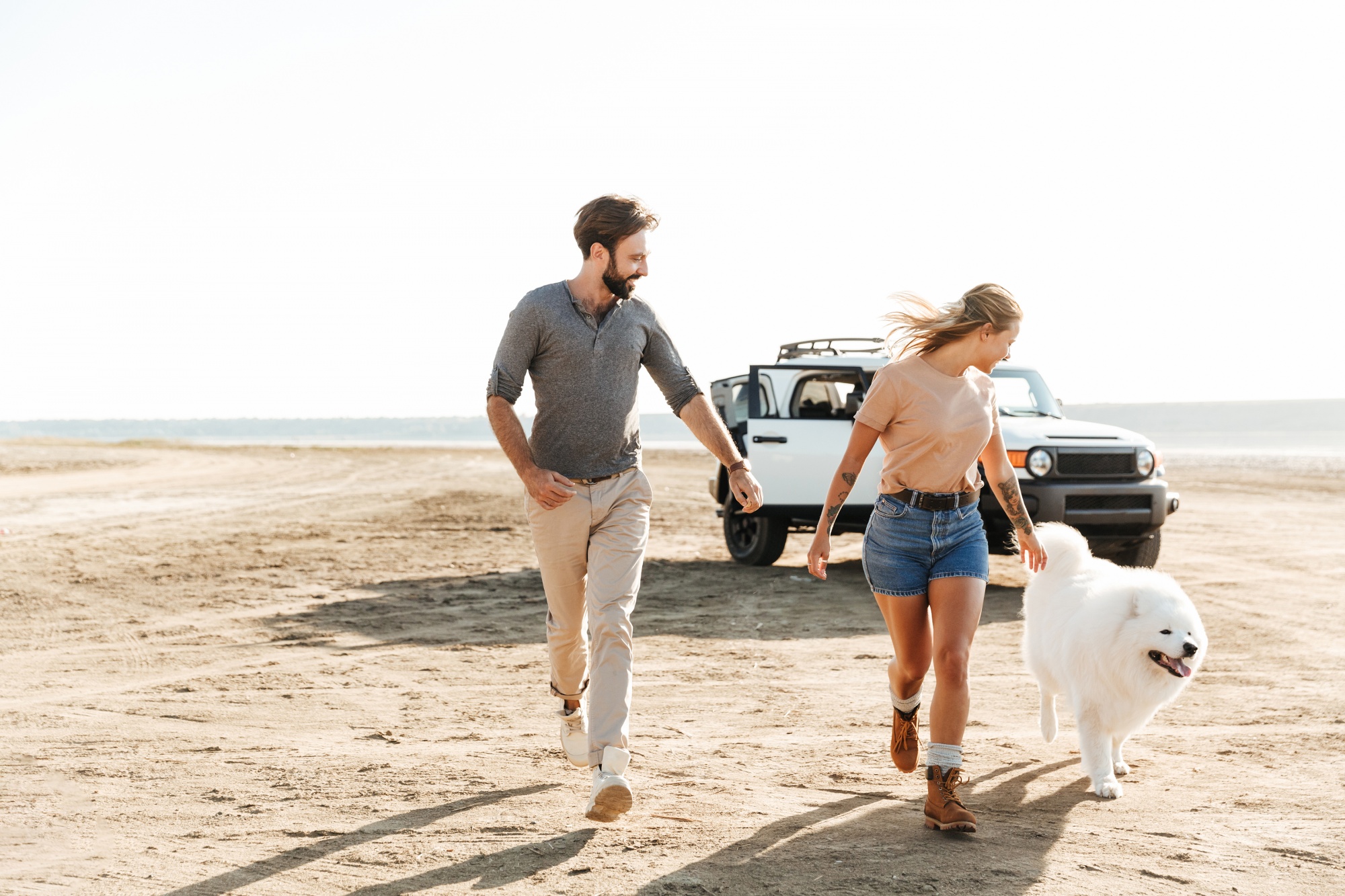 dogs save empty nesters, active couple running with their beautiful white dog on the beach