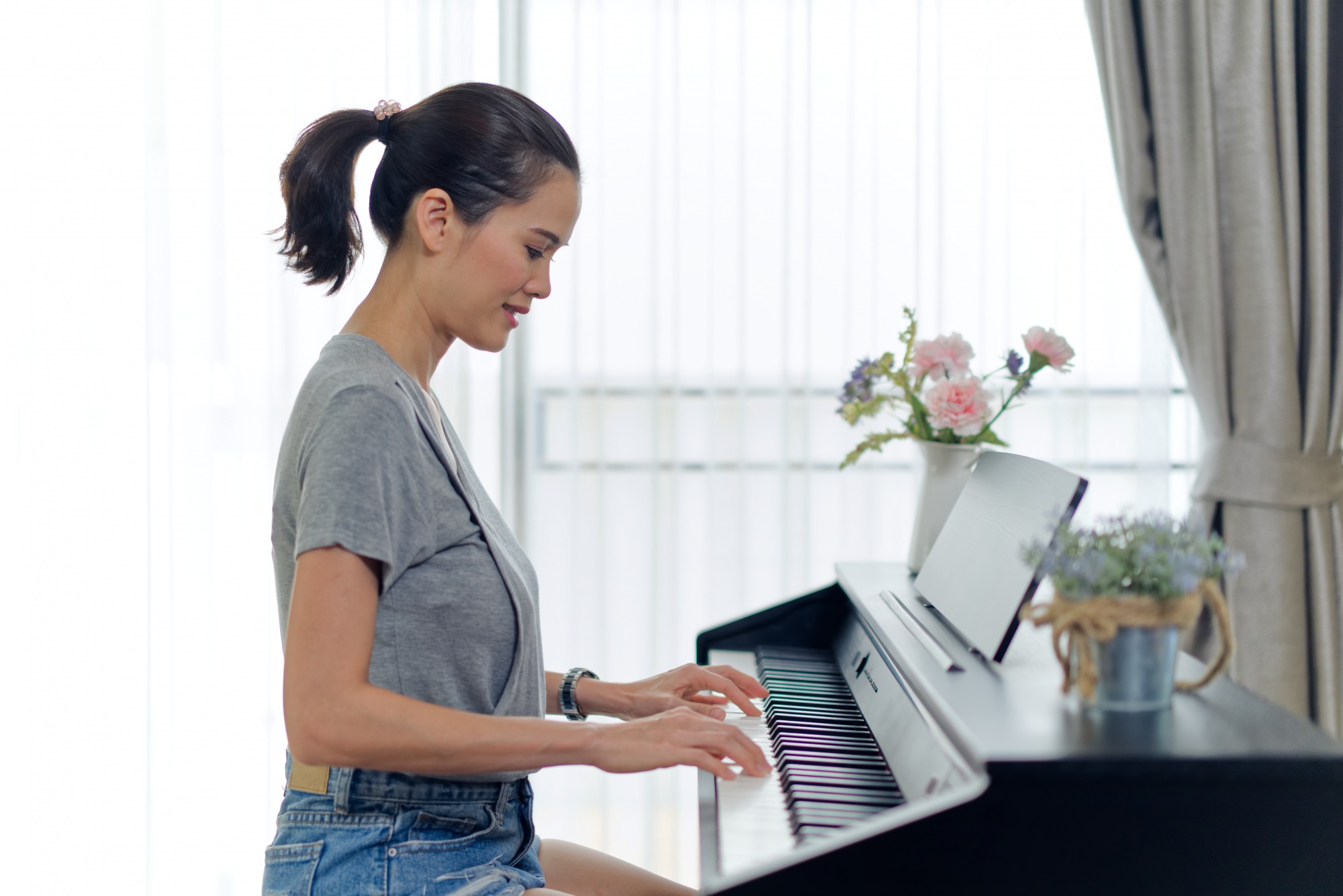 What is neuroplasticity? Asian woman in denim shorts and grey tank playing piano
