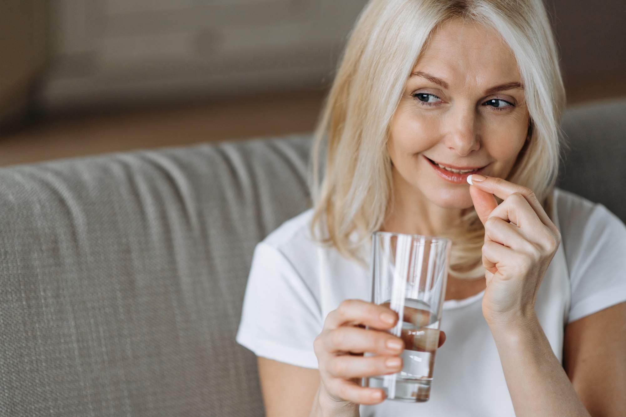 get rid of mummy tummy for good, Blonde bobbed woman on couch taking supplement