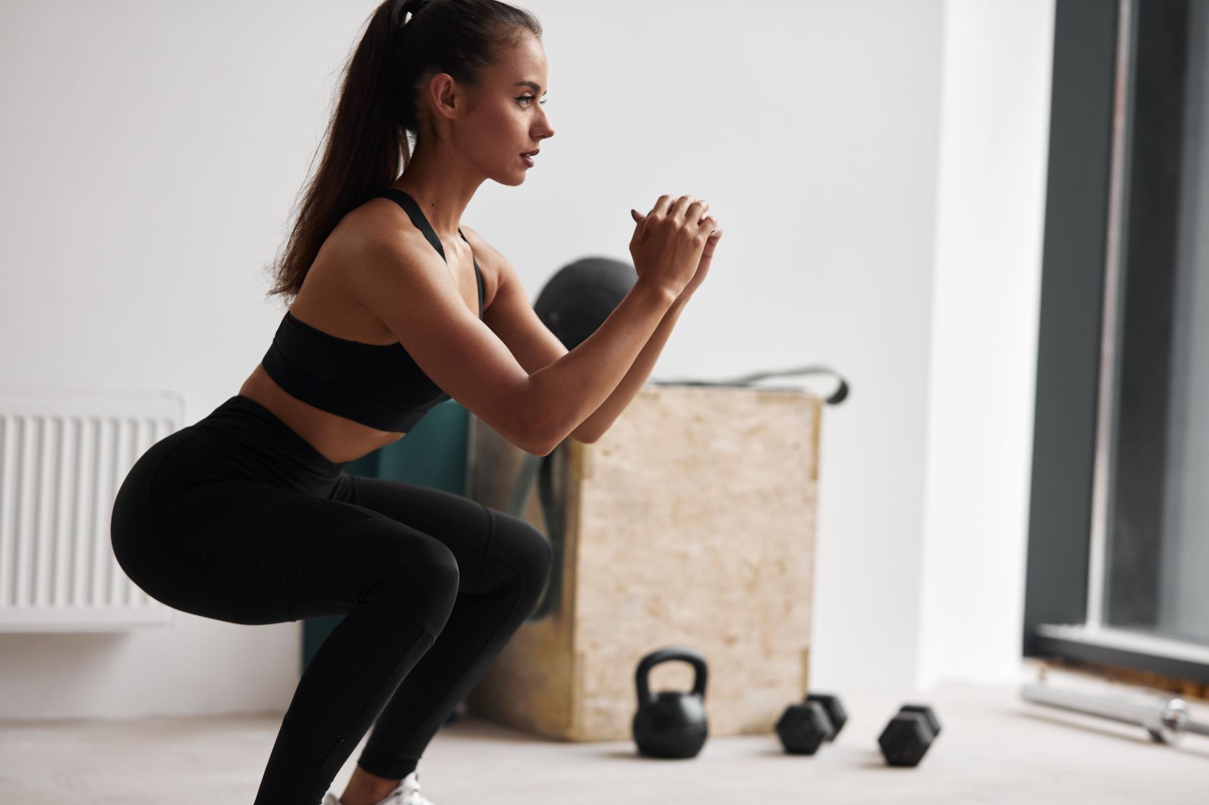 How to Avoid Exercise Injury Over 40, Dark haired woman in black in squat