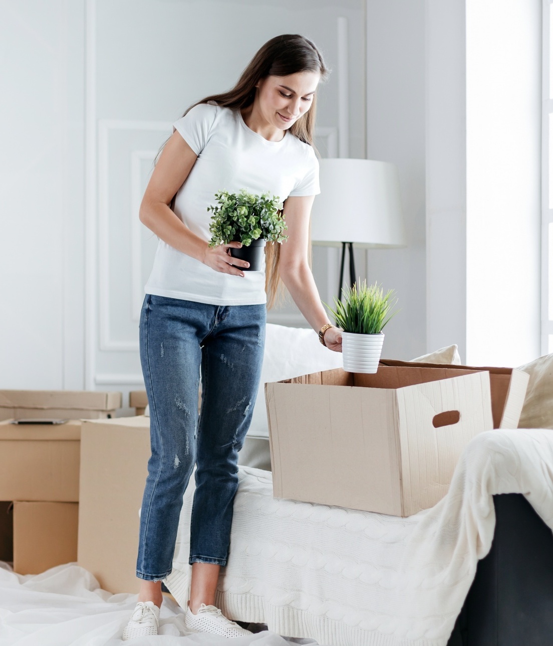 why reinventing yourself makes you younger, Dark haired woman in cropped jeans and white tee unpacking boxesDark haired woman in cropped jeans and white tee unpacking boxes