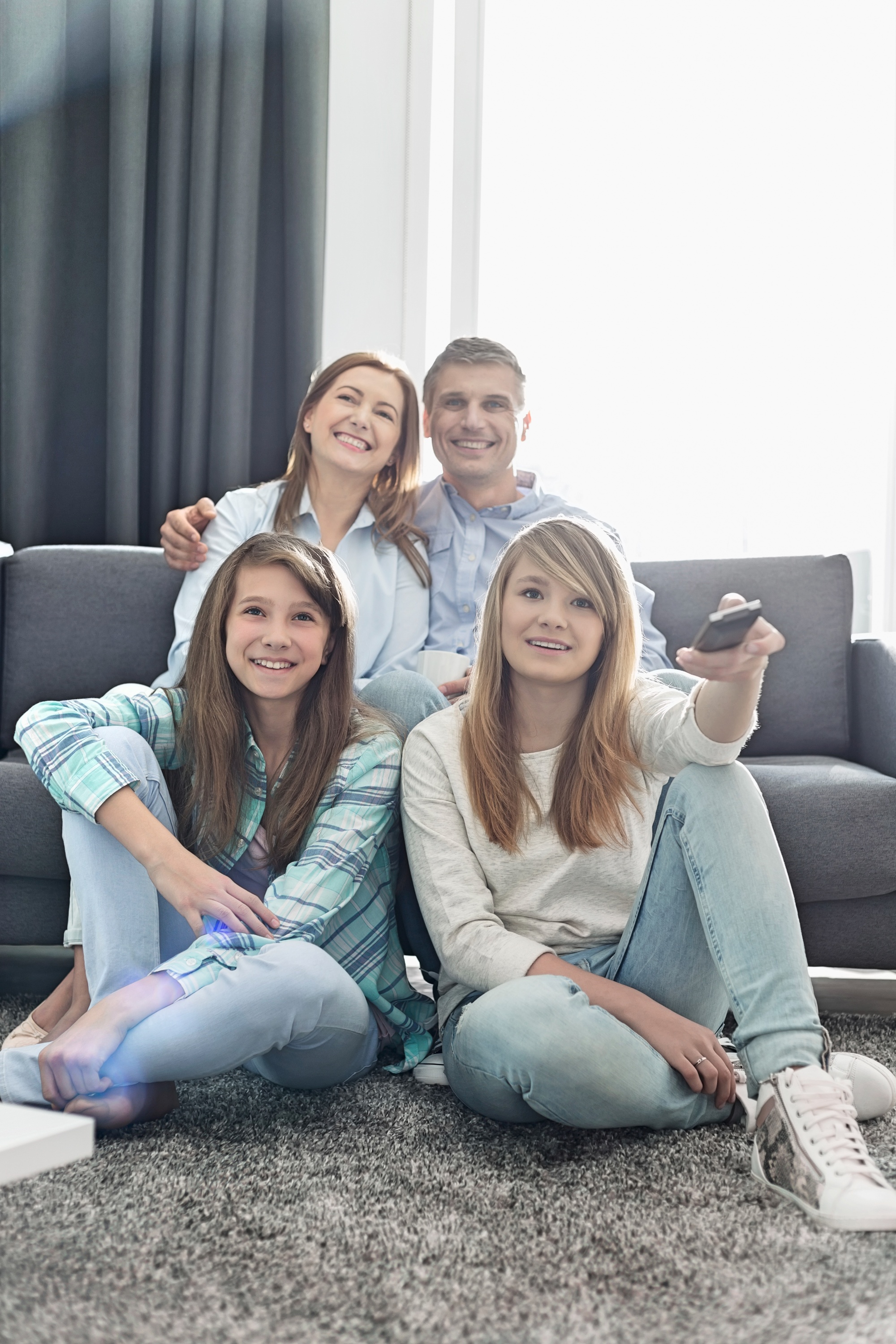 binge watch with your teens, mom and dad and two teen girls watching TV in the living room