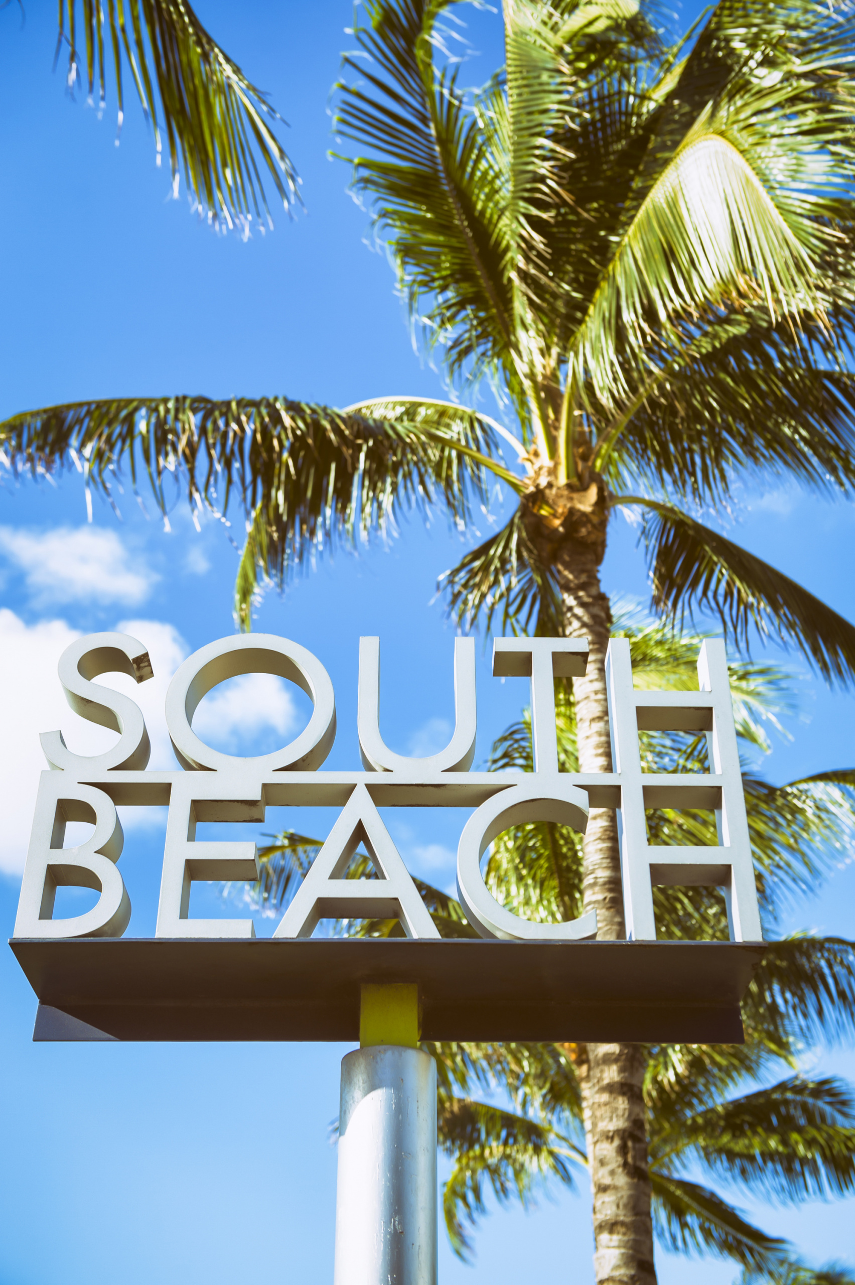 miami vacation guide, south beach sign on a sunny day in front of palm trees