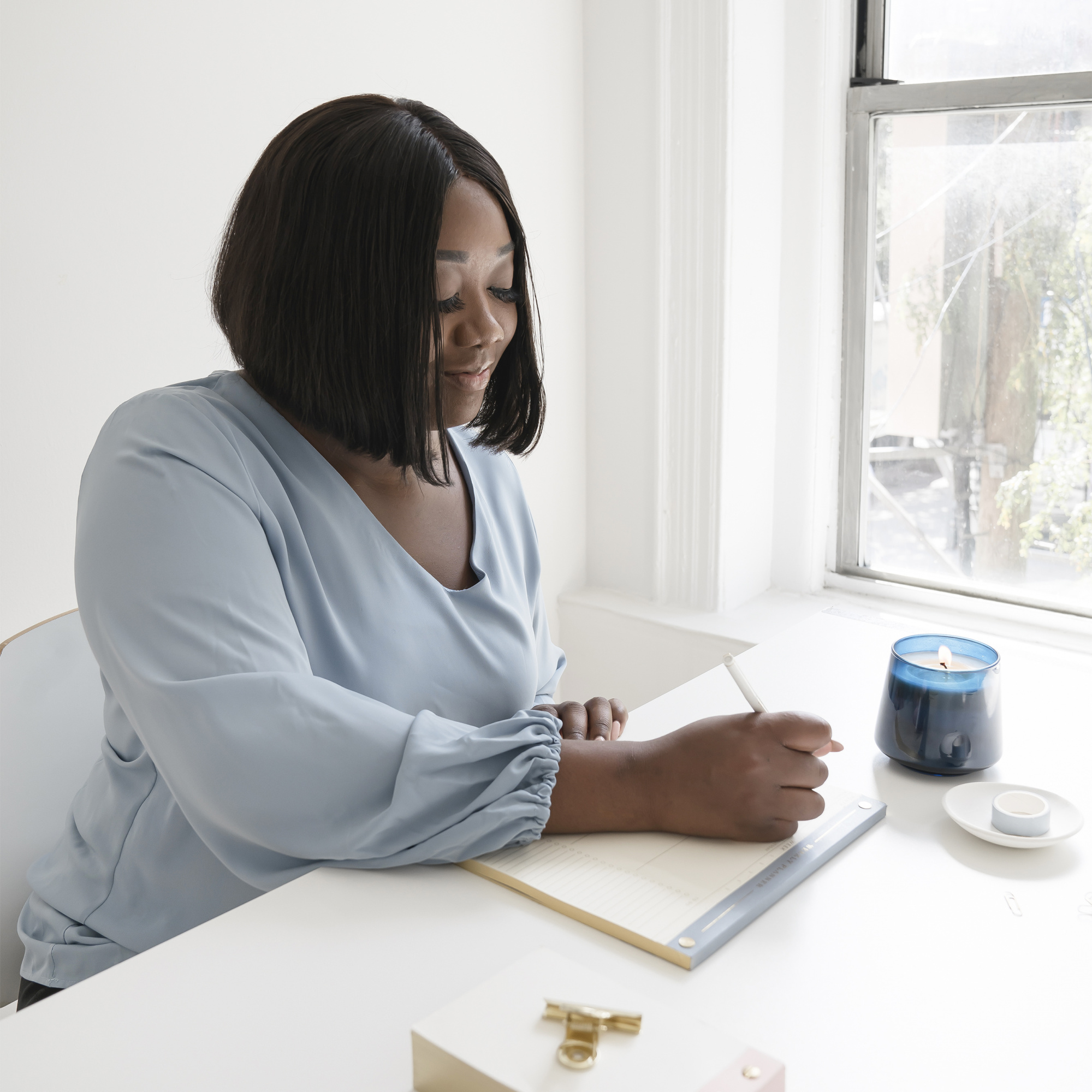 common menopause questions, Black woman with chin-length hair in blue blouse writing