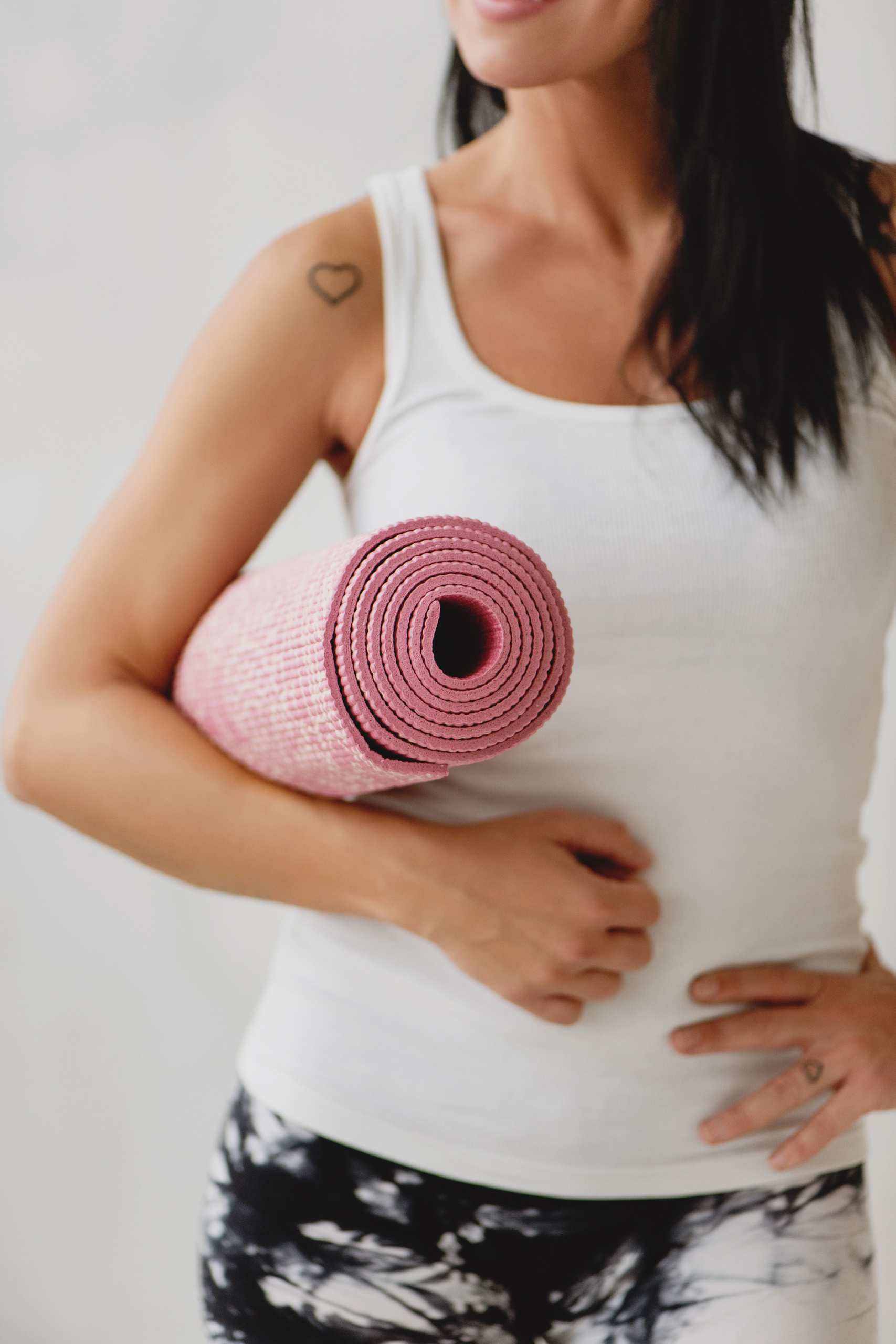 common menopause questions, Slim woman in white tank and marbled leggings with pink yoga mat