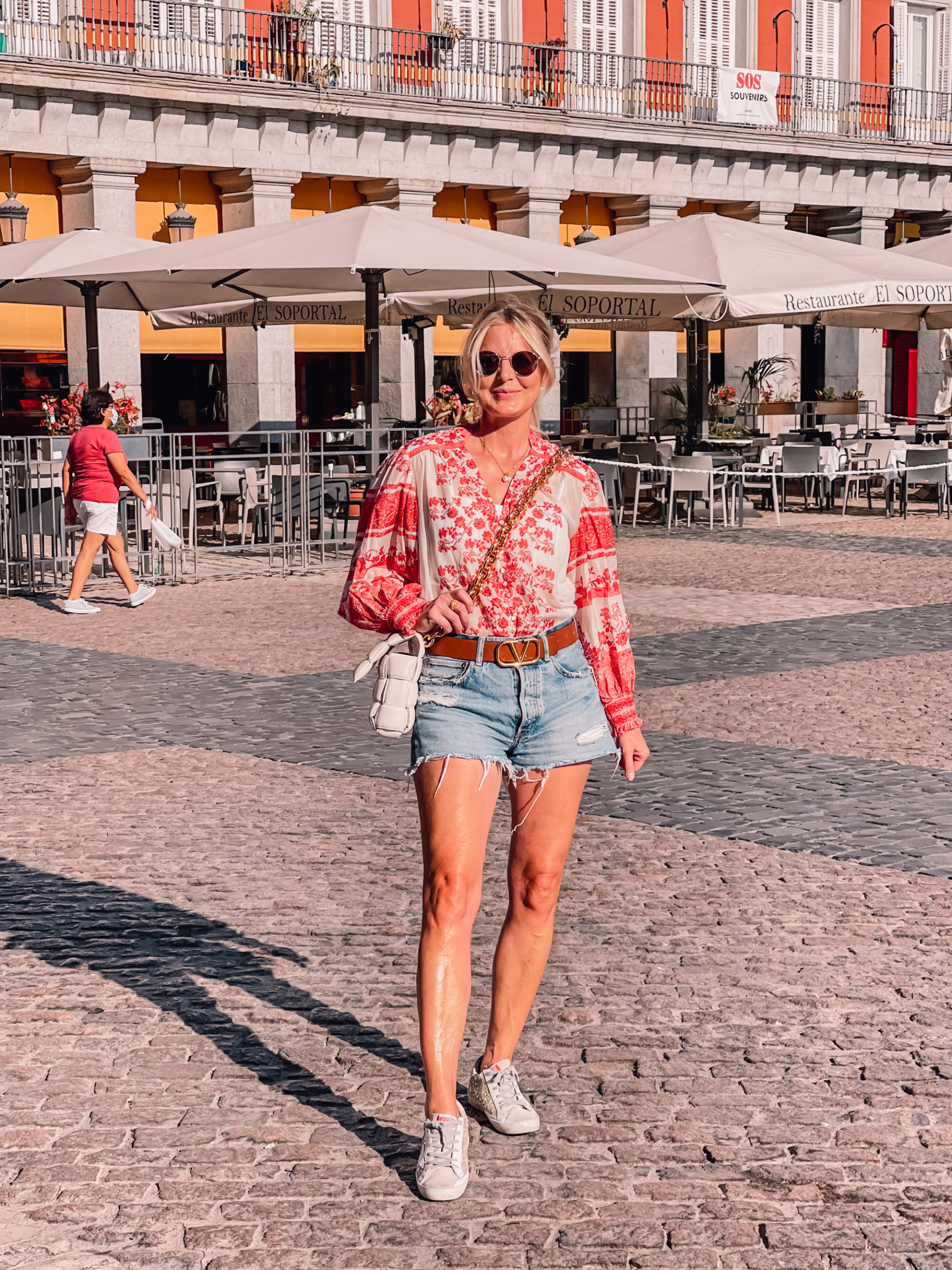 what to wear in spain, how to dress in spain, madrid, how to dress in madrid, what to wear in madrid, how to pack for a trip to spain, trip to spain, packing for spain, erin busbee, alice + olivia red printed blouse, moussy denim shorts, golden goose sneakers, bottega veneta chain cassette bag, valentino belt