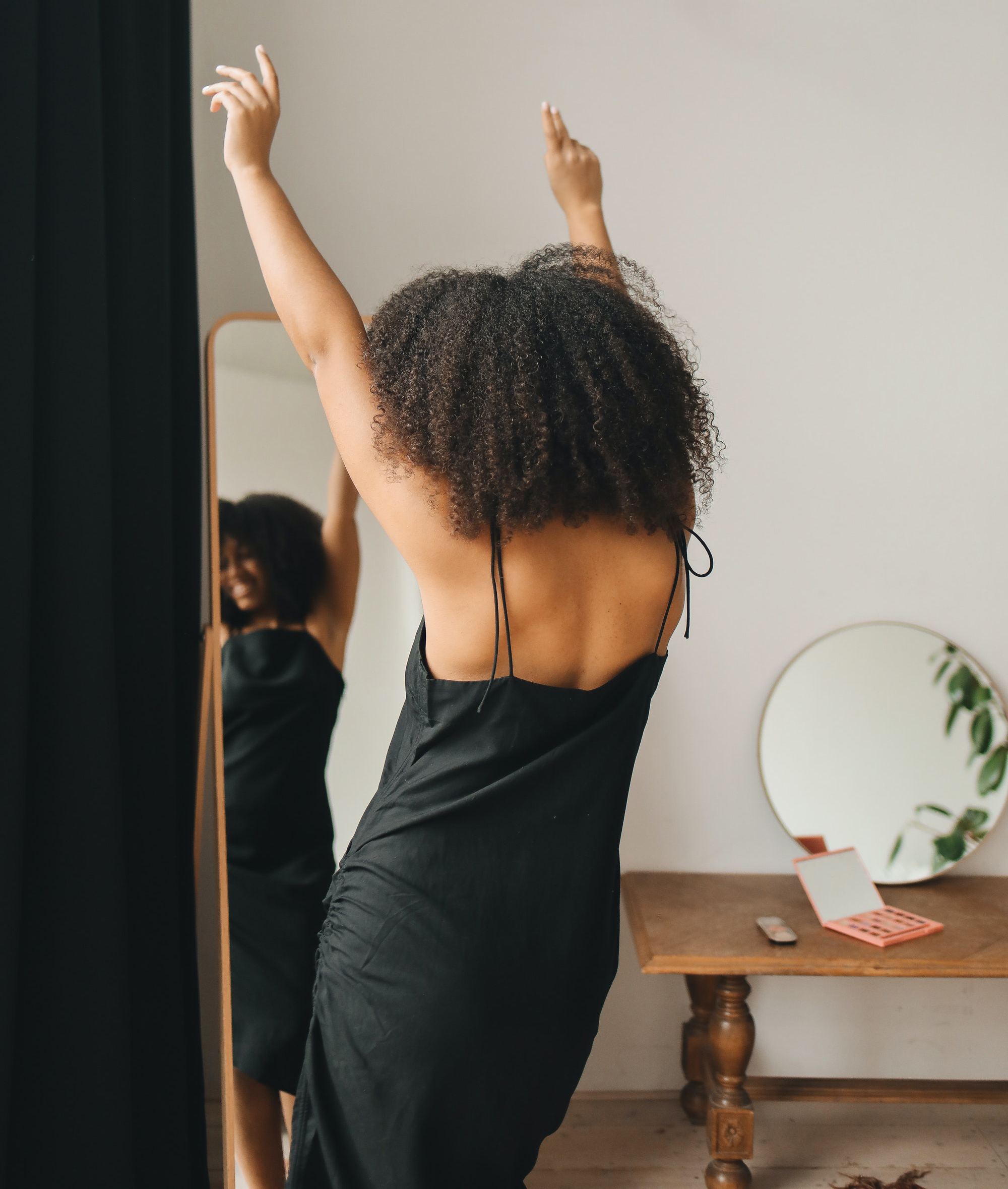 Redefining Your Style, African American woman happy dancing getting dressed in the mirror, 5 Tips for Redefining Your Style and Feeling Beautiful After Breast Cancer