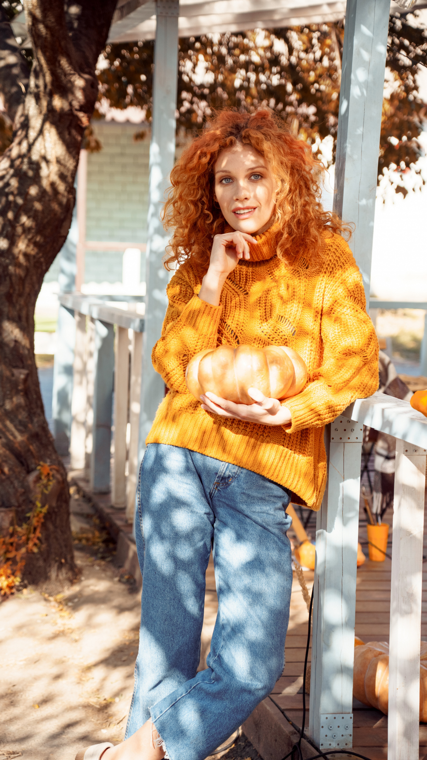 autumn self-care products, Red-haired woman in gold sweater and jeans holding pumpkin
