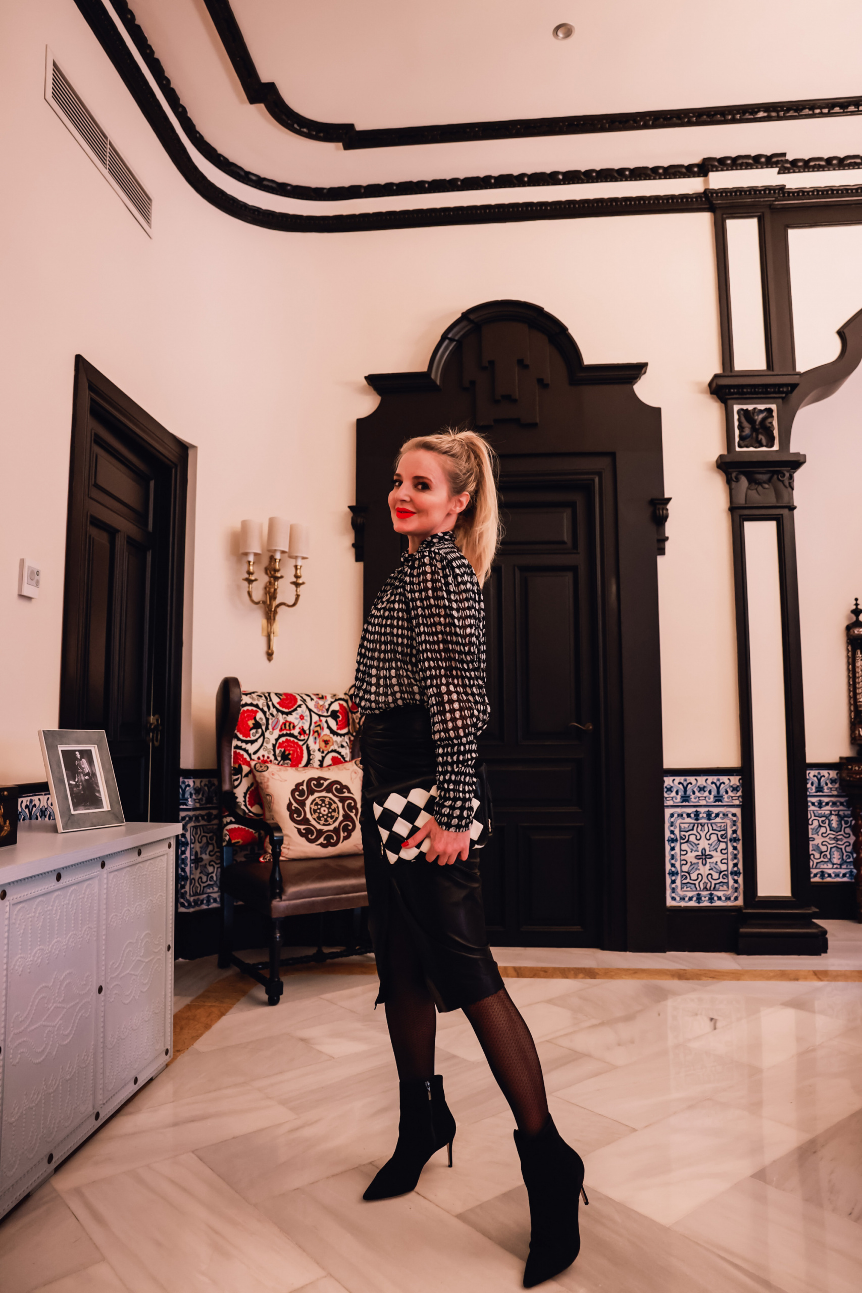 office outfits, stylish office outfits, chic office outfits, office outfits over 40, workwear over 40, stylish workwear, erin busbee, iro black leather midi skirt, ba&sh printed blouse pointed toe schutz boots, ba&sh black and white checkered bag, sevilla, spain, office to date night outfit