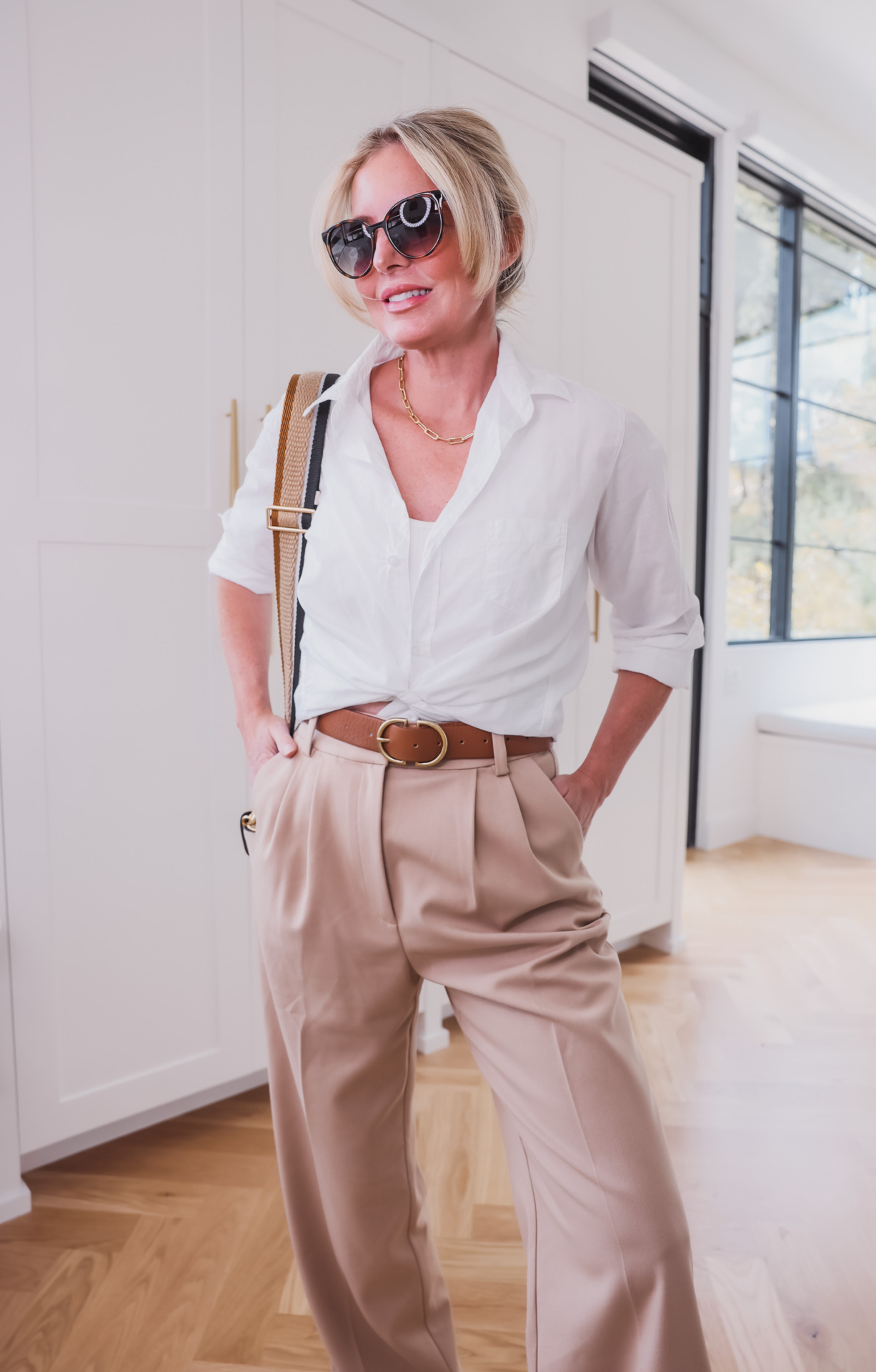 how to wear pleated pants, ways to wear pleated pants, ways to style pleated pants, how to style pleated pants, pleated trousers women, pleated pants over 40, favorite daughter pleated pants, pleated pants 2023, pleated pants outfits, erin busbee, busbee style, fashion over 40, eileen fisher white button down shirt, new balance 327 sneakers, le spec sunglasses, madewell belt, marc jacobs tri-color handbag