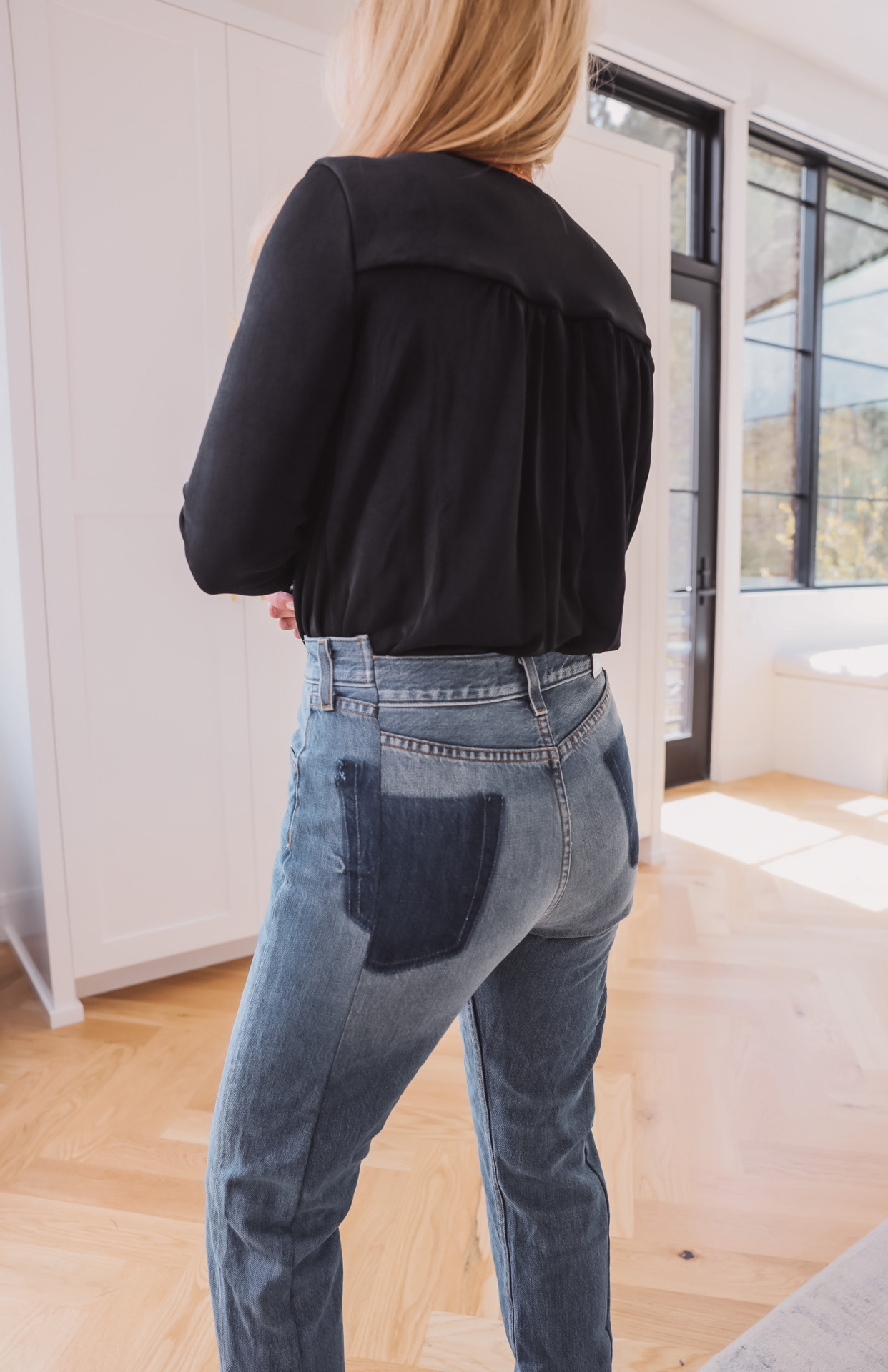 woman showing back details of the Split seam jeans and black top for jean trends
